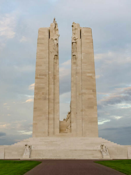 Monument du Mémorial canadien de Vimy au coucher du soleil, vu de face, sur fond de ciel nuageux.