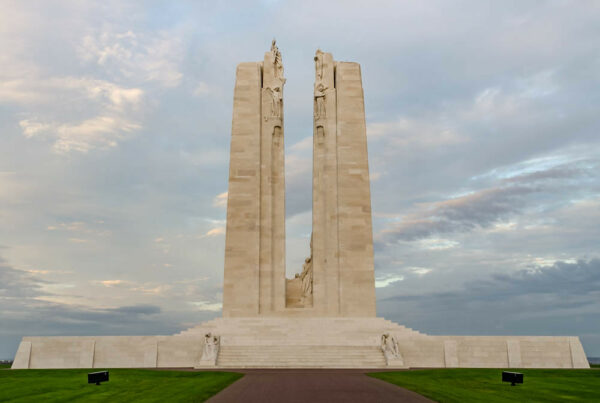 Monument du Mémorial canadien de Vimy au coucher du soleil, vu de face, sur fond de ciel nuageux.